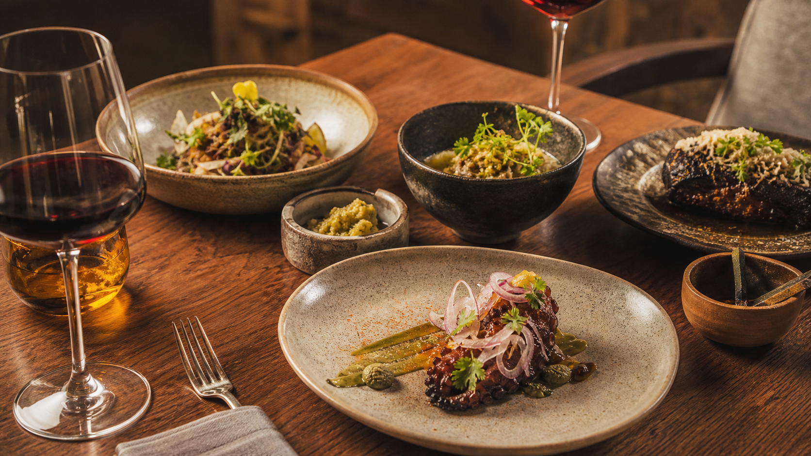 Platillos mexicanos contemporáneos y copas de vino en una mesa de experiencia gastronómica.